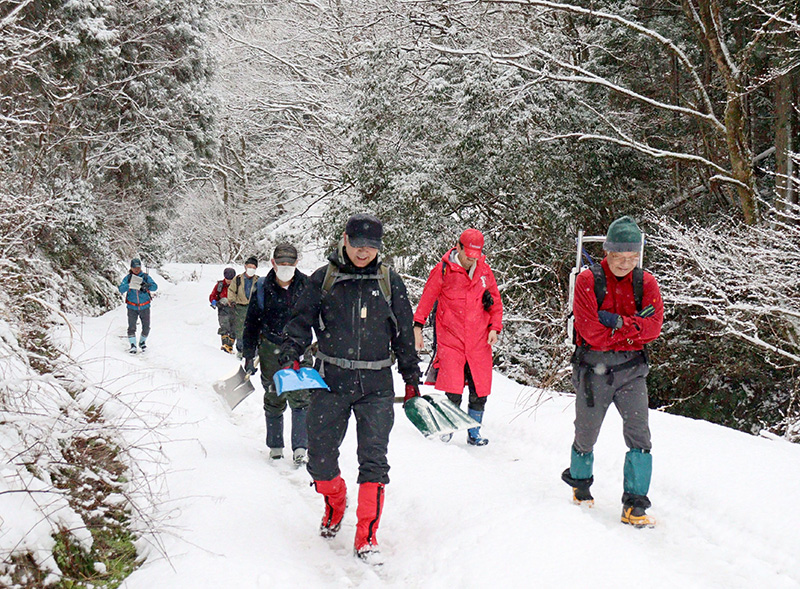 寒九の水くみで、清水を入れたポリタンクを背負って下山する参加者ら=2022年1月、五泉市の菅名岳