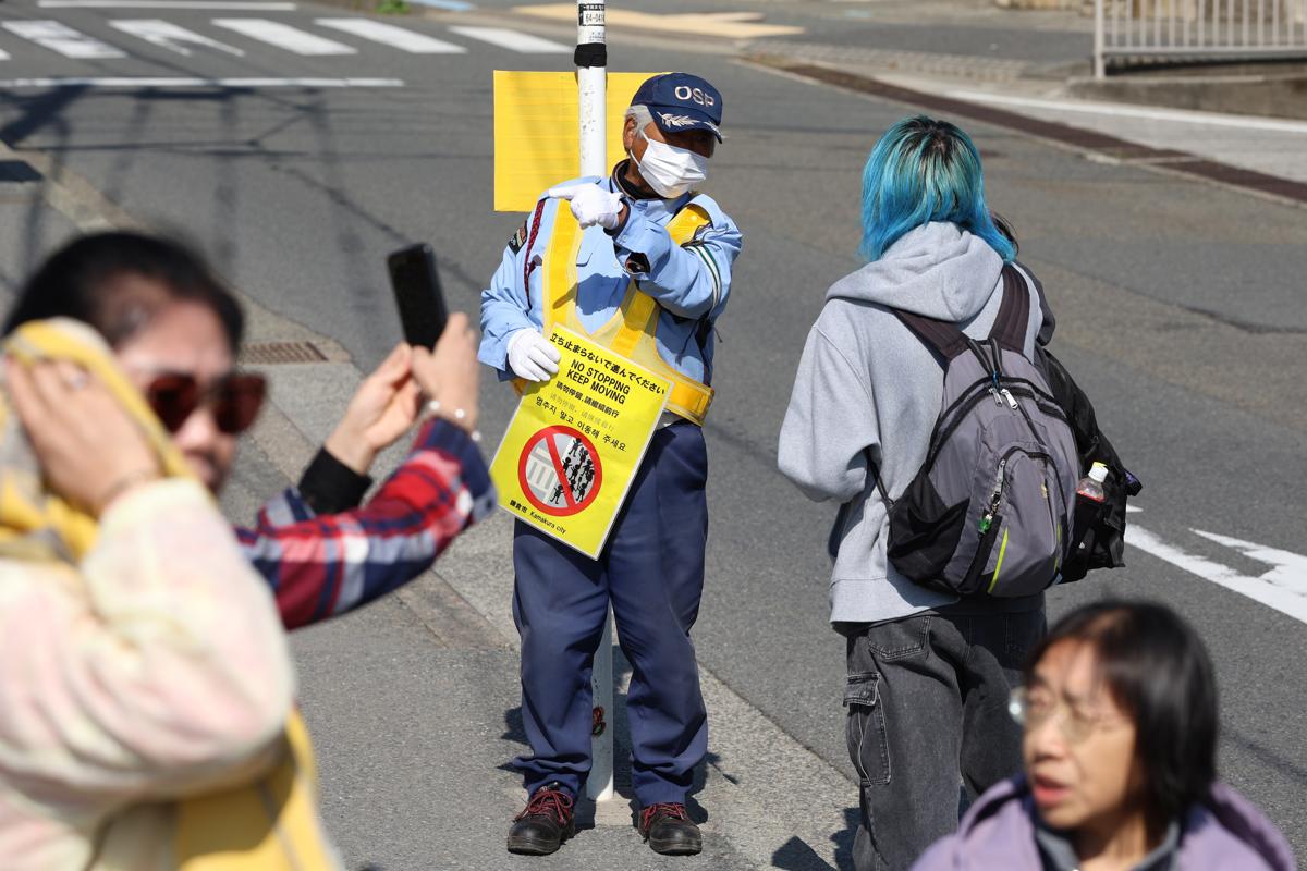 
観光客と会話する警備員。警備するだけでなく、道を尋ねられることもある。複数言語で対応している＝10月、鎌倉市
