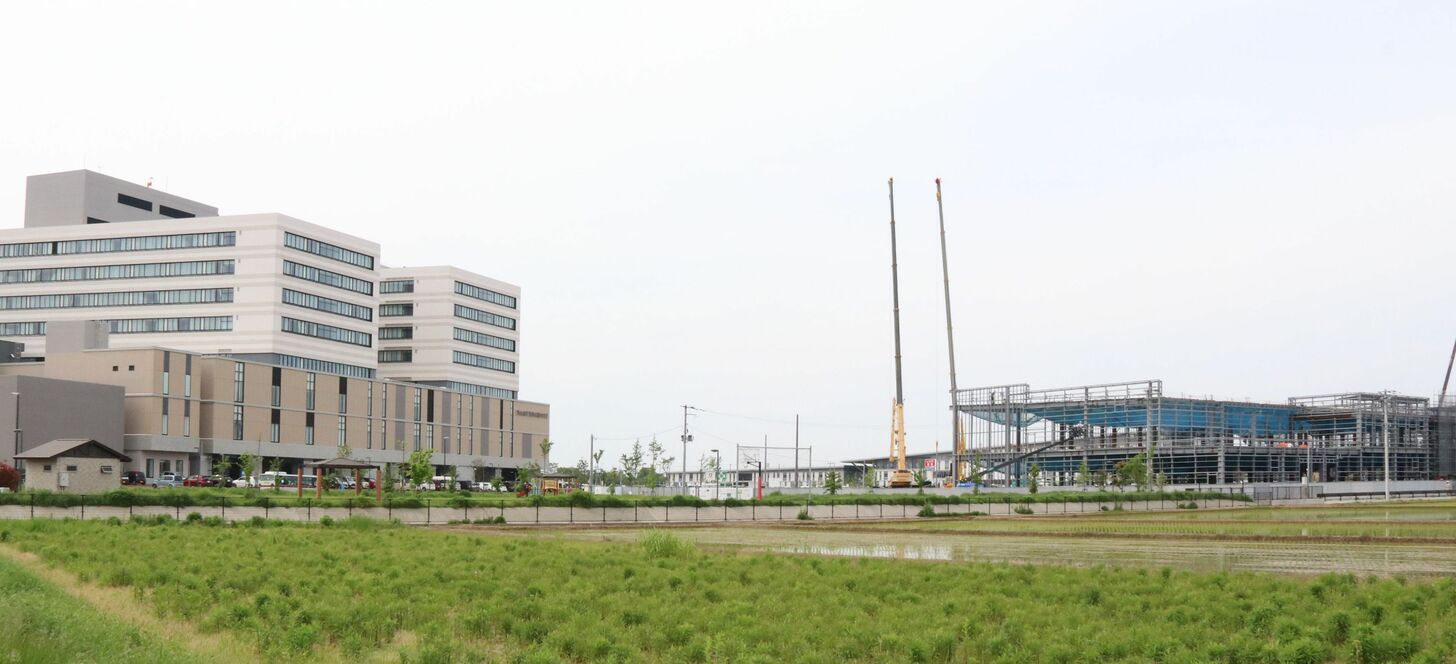 建設中の商業施設「（仮称）イオン三条上須頃」（右）。近隣には済生会新潟県央基幹病院（左）や三条市立大学がある＝５月１５日、三条市上須頃