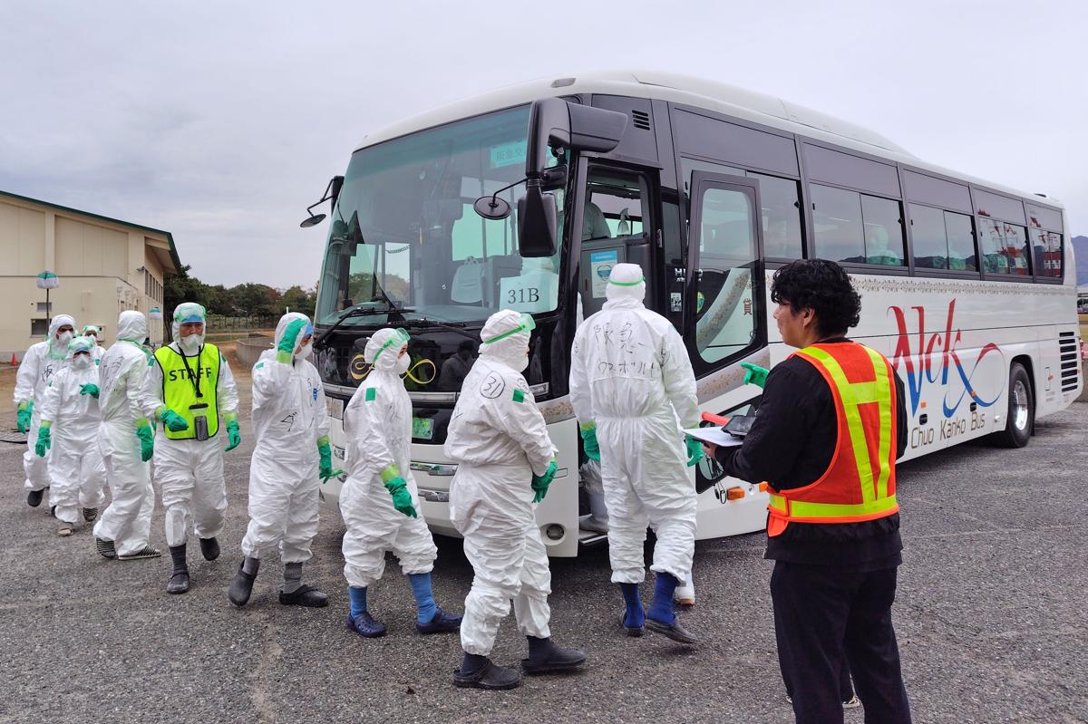 防疫作業のため養鶏場に向かう作業員ら＝９日午前８時前、胎内市