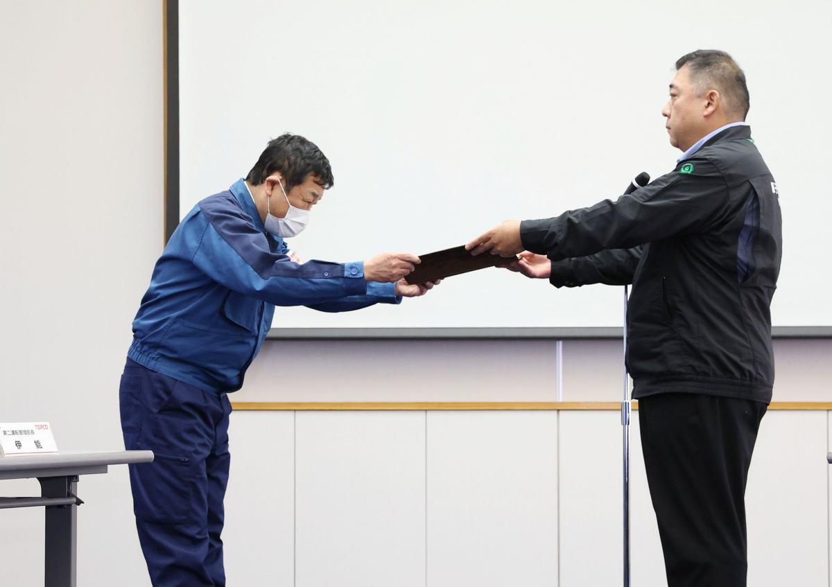 
原子力規制委員会から交付された「使用前確認証」を受け取る東京電力柏崎刈羽原発の稲垣武之所長（左）＝１６日、柏崎刈羽原発
