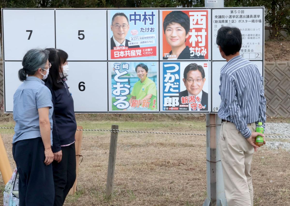 
衆院選１区の候補者ポスターを見つめる曽我ひとみさんの同級生。拉致問題の進展がない中、複雑な心境で選挙戦を見守る＝佐渡市
