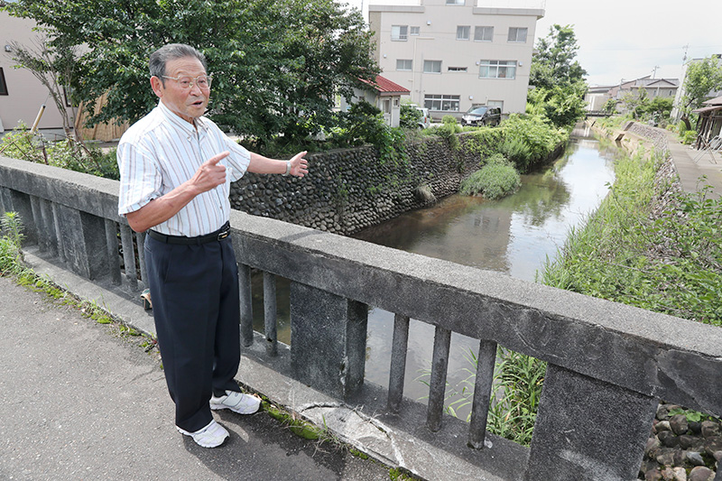 長岡空襲の夜を過ごした柿川の霞橋に立つ白石美千雄さん＝長岡市柳原町