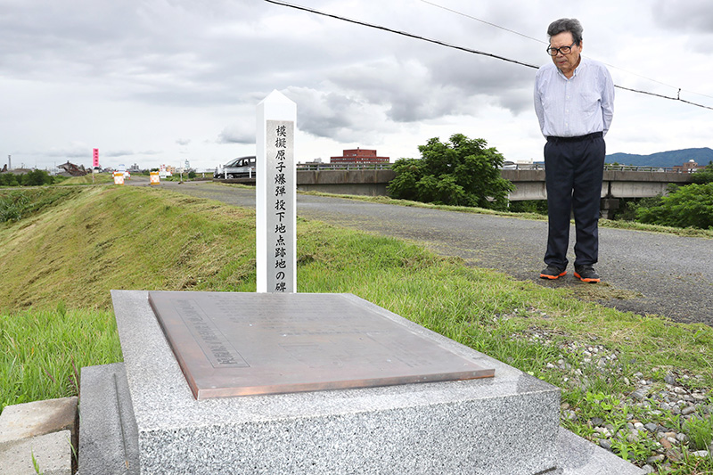 空襲後の神明神社の様子を父から聞いた今泉弥さん。手前は犠牲者を悼む慰霊碑＝長岡市柳原町