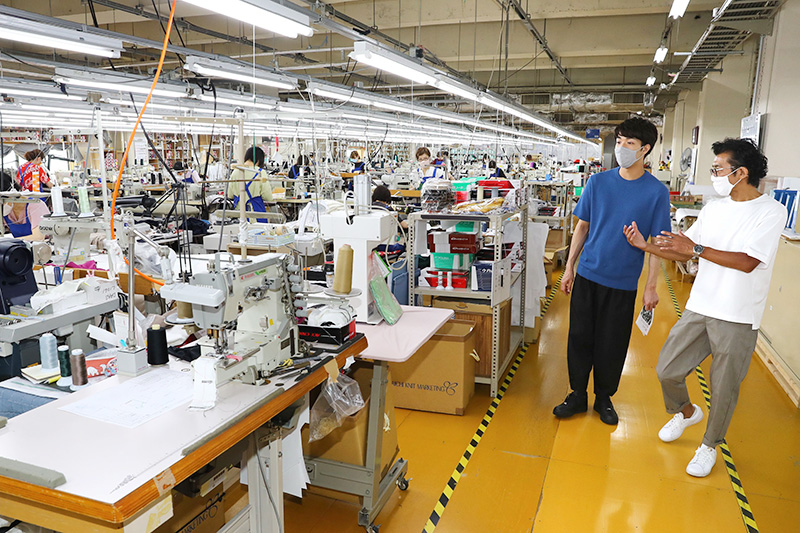 第一ニットの工場を見学する中澤卓也さん（左）。縫製作業のスムーズな流れに感心していた＝見附市柳橋町