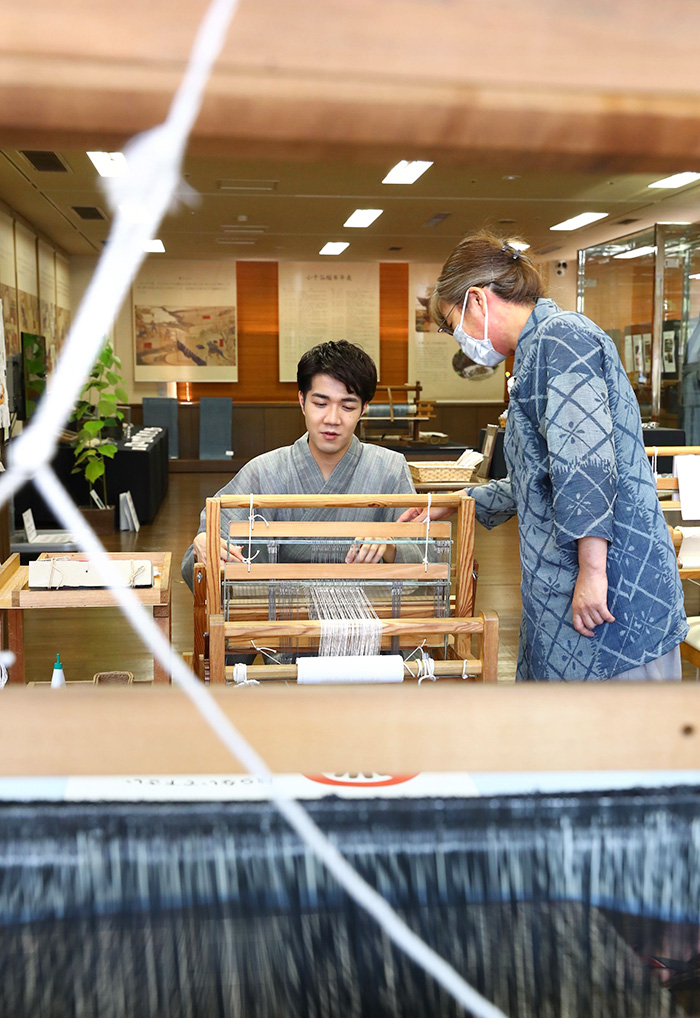 機織りを体験。伝統の作業に夢中になった＝サンプラザ内の織之座