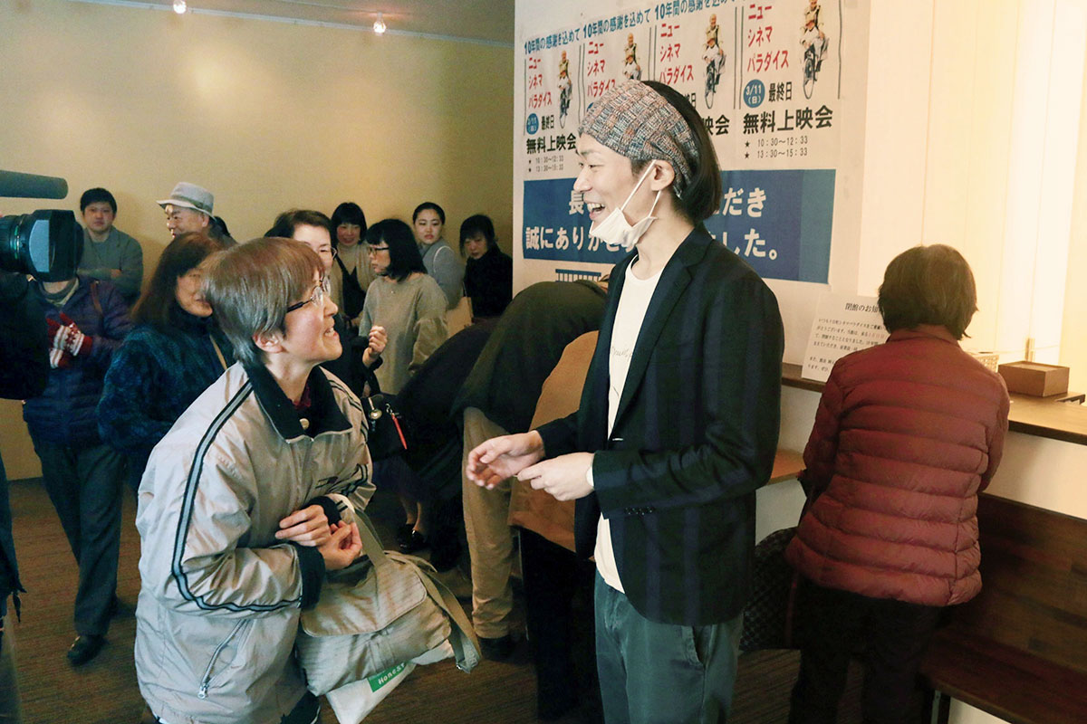 「十日町シネマパラダイス」の閉館日。観客と言葉を交わす副館長の岡元豪平さん（中央右）＝2018年3月