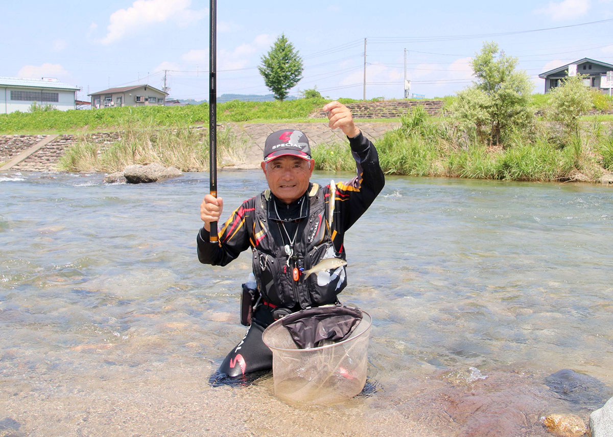 ホームグラウンドの佐梨川でアユを釣り上げる桑原貞雄さん＝魚沼市佐梨