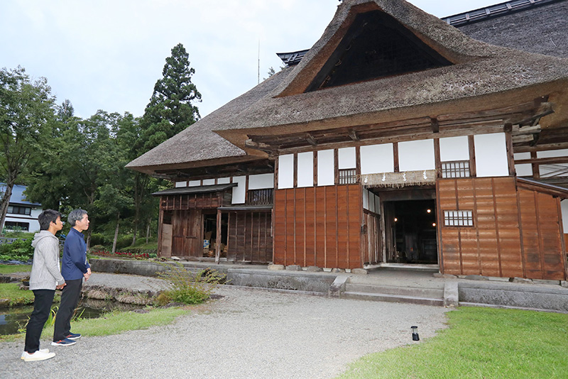 「目黒邸」を見学する加藤さん。かやぶきの屋根が印象的な主屋は、重厚なたたずまいだ＝魚沼市須原