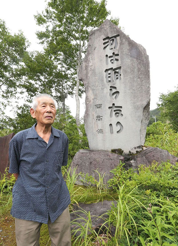文学碑の前で、開高との思い出を振り返る佐藤進さん＝８月、魚沼市湯之谷地域