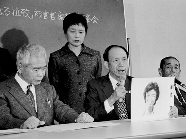 「『北朝鮮による拉致』被害者家族連絡会」の会見で、蓮池薫さんの顔写真を手に、救出を訴える父秀量さん（中央）。後ろは母ハツイさん＝１９９７年３月、東京・参院議員会館